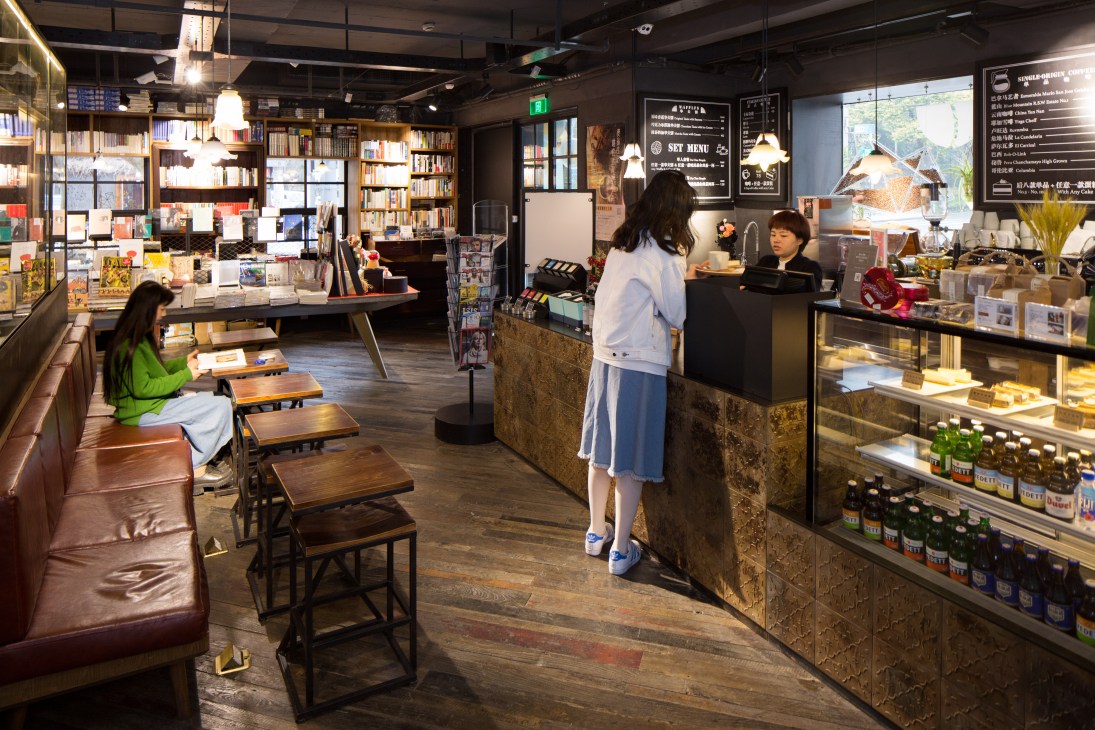Customer at counter of The Mix Place bookshop café in Shanghai with shelves of products and books visible.