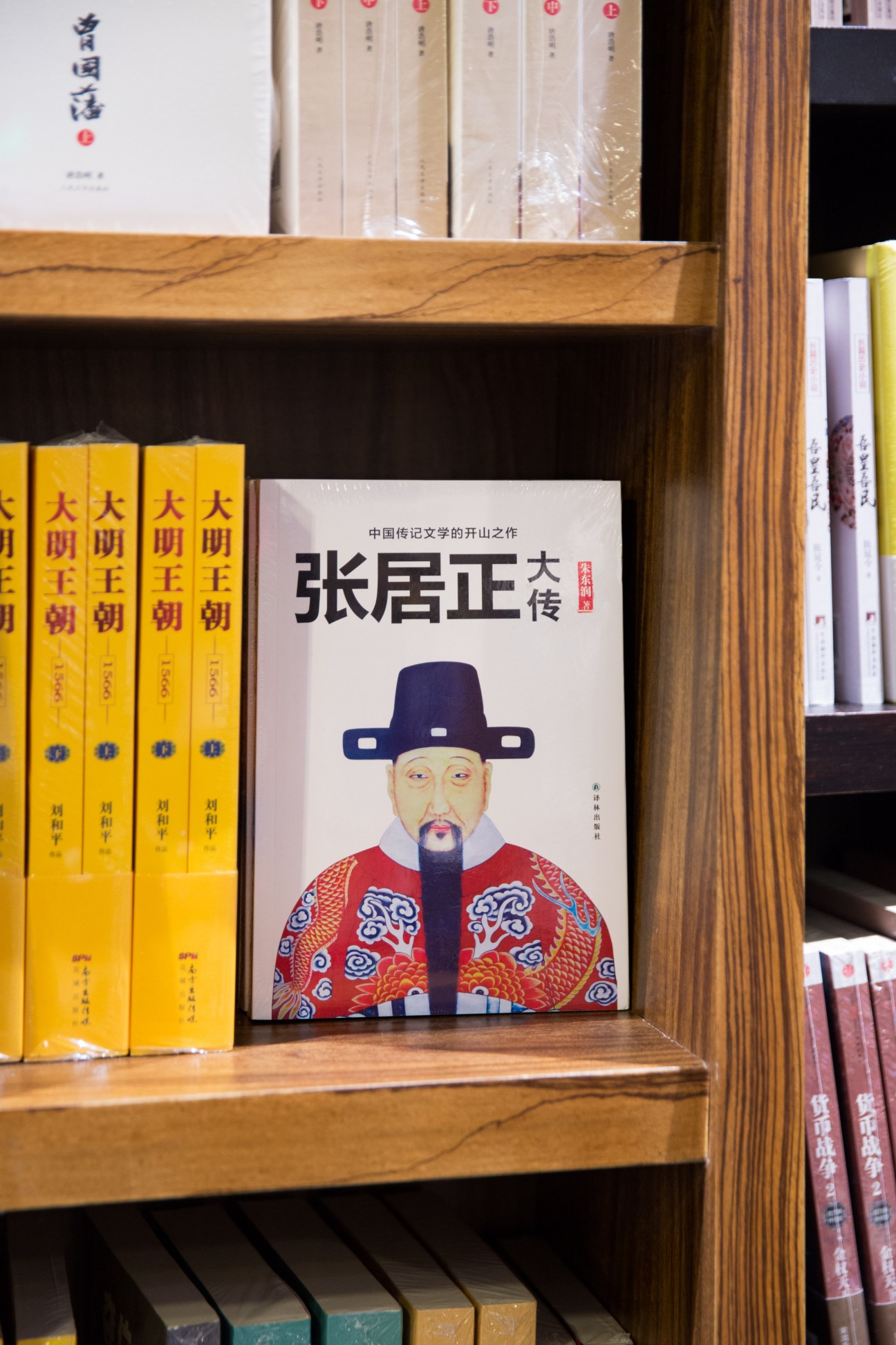 Wooden bookshelf displaying Chinese classic novels with yellow spines and a book featuring traditional portrait artwork.