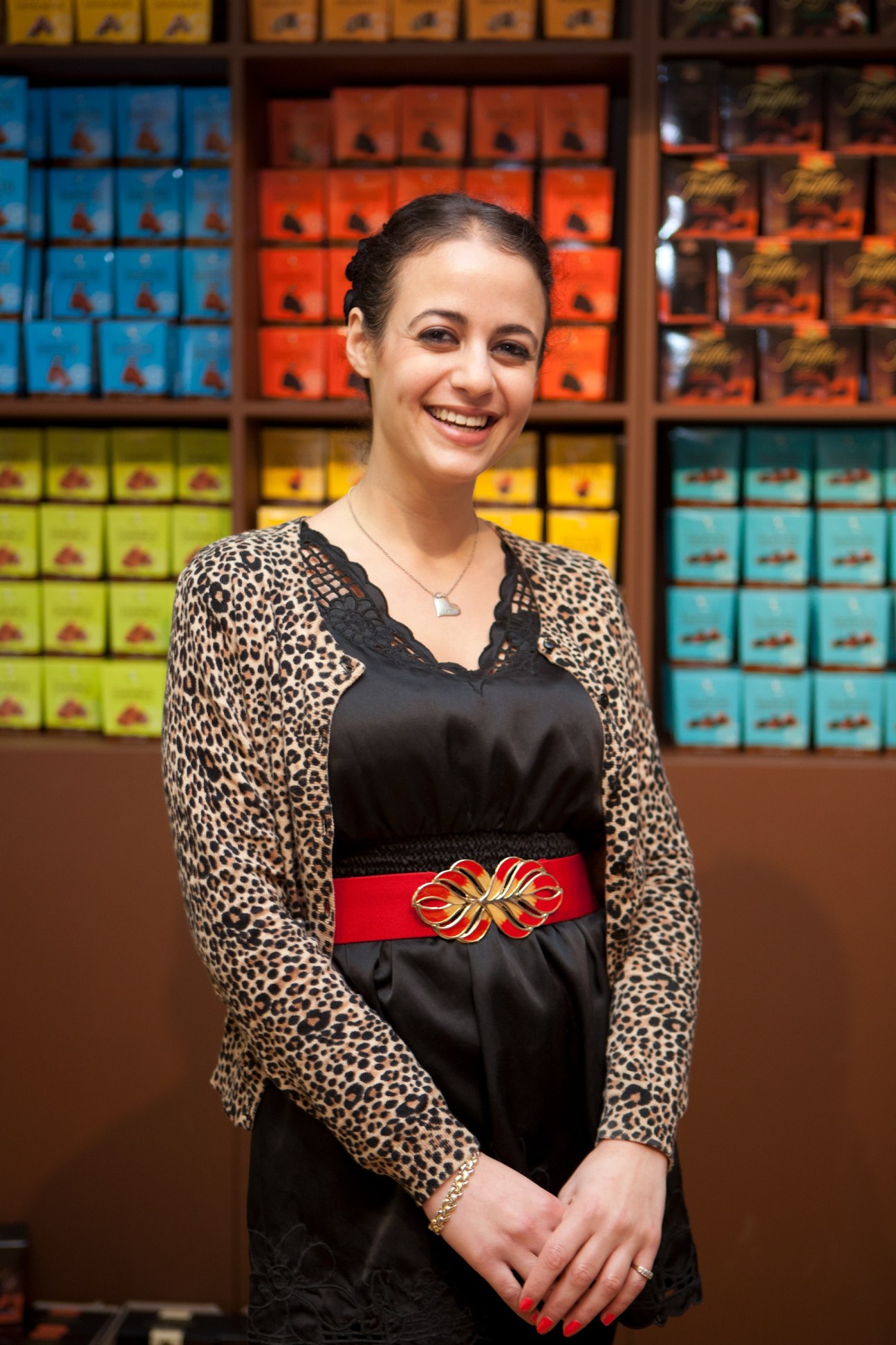 Rotem Lichak from Truffettes de France smiling in front of colorful chocolate boxes at the New York Chocolate Show.