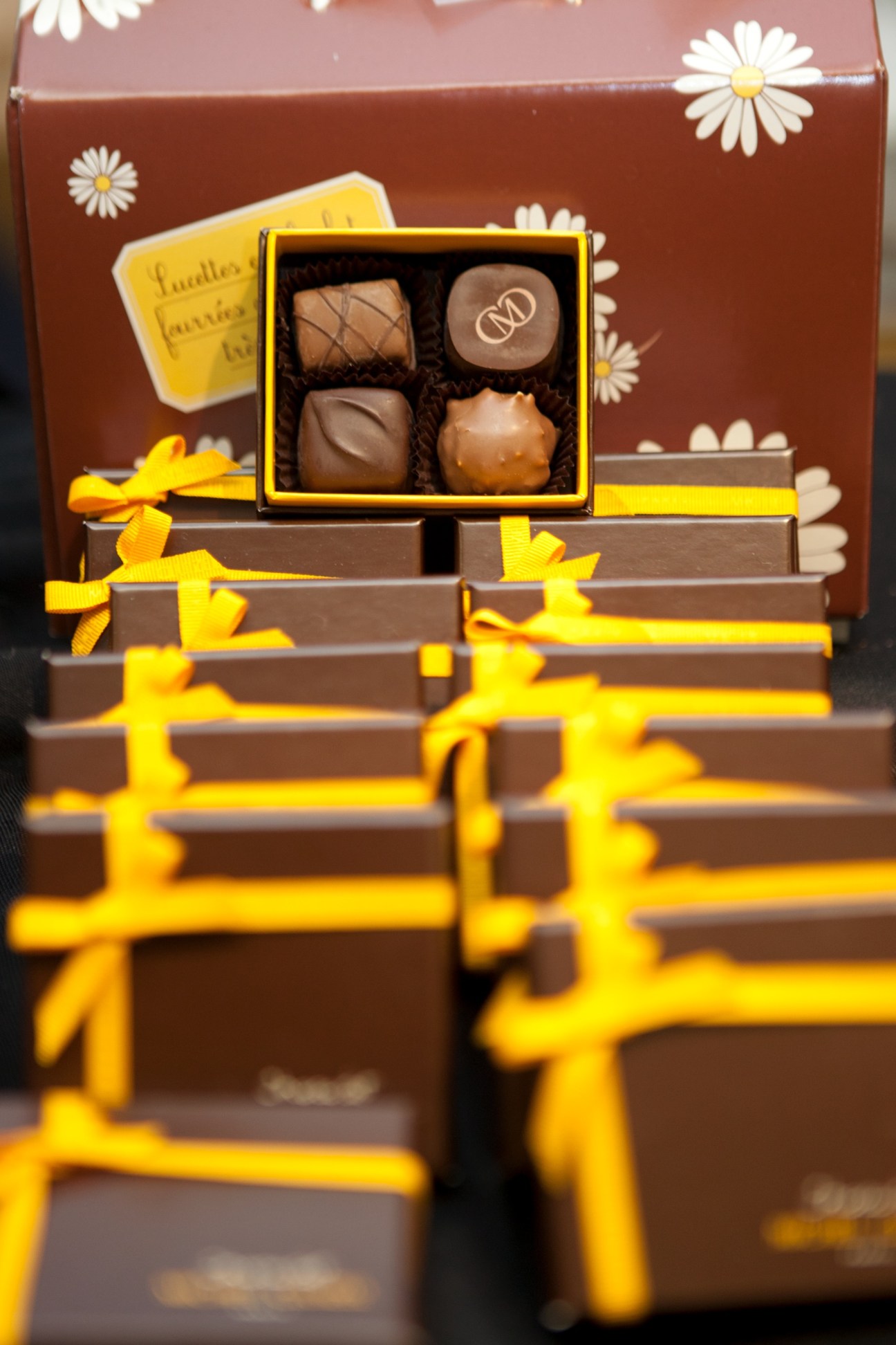 Michel Cluziel chocolate truffles in a yellow box with brown packaging decorated with white daisies and yellow ribbons.