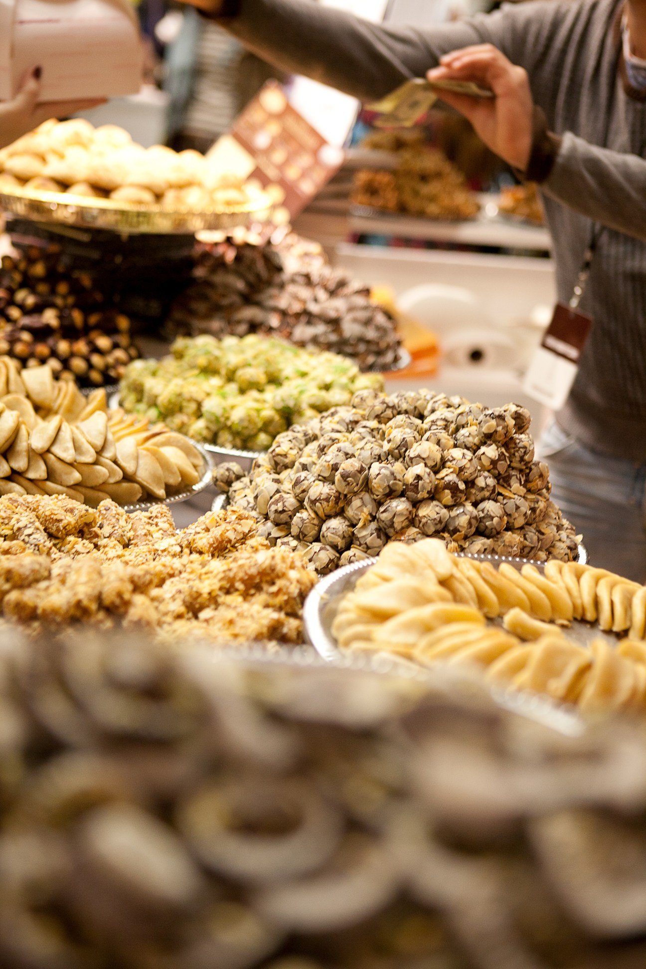 Moroccan pastries and confections displayed at La Gazelle D'Or booth with visitor sampling products.