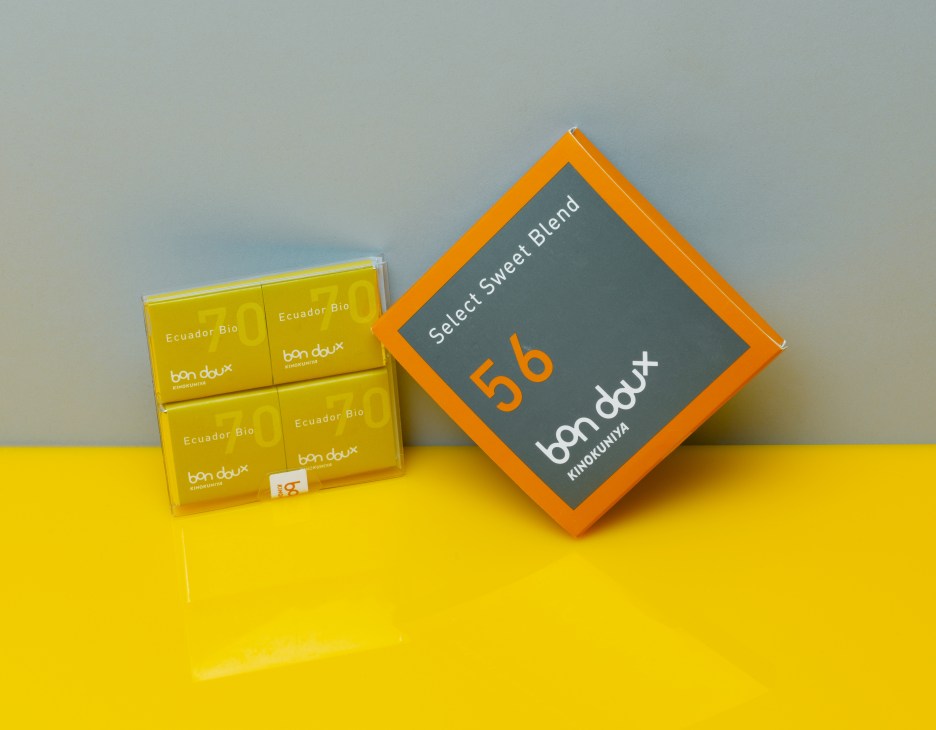Bon Doux chocolate boxes with yellow Ecuador Bio packaging and orange branded gift box on yellow surface.