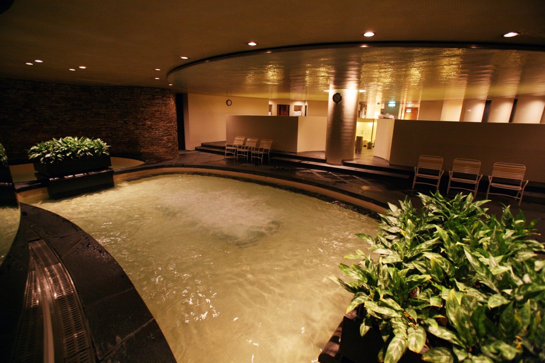 Indoor spa facility with large hot spring communal bath, wooden loungers, and ambient lighting at Grand Hyatt Seoul.