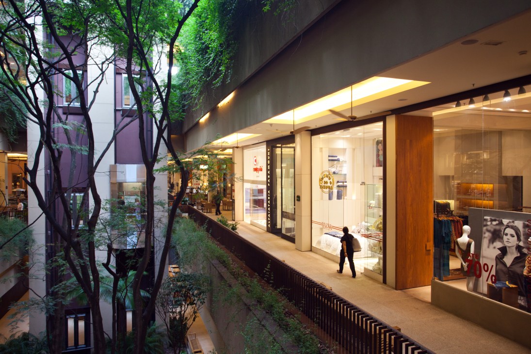 Open-air shopping balcony with luxury retail storefronts, lush greenery, and modern architectural design at Cidade Jardim mall.