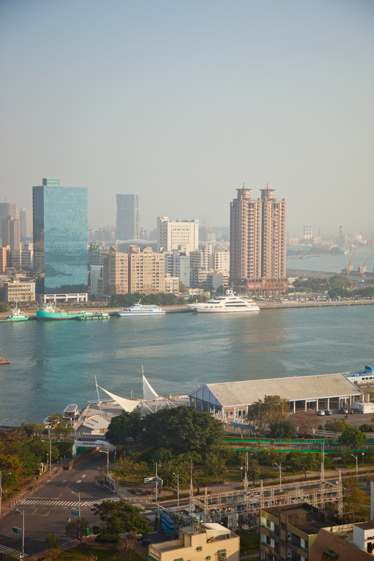 Kaohsiung cityscape with modern skyscrapers, yachts moored in the harbor, and waterfront development.