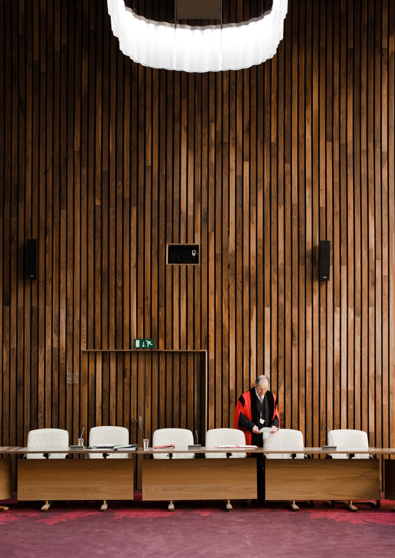 Interior of the Corby Cube with wooden slat walls, curved ceiling light, and a person at a long desk.