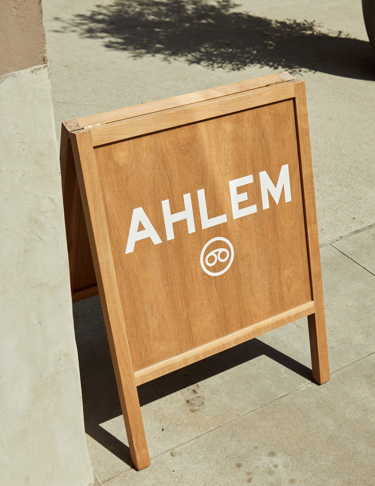 Wooden A-frame sidewalk sign displaying Ahlem brand name and logo outside the eyewear store.