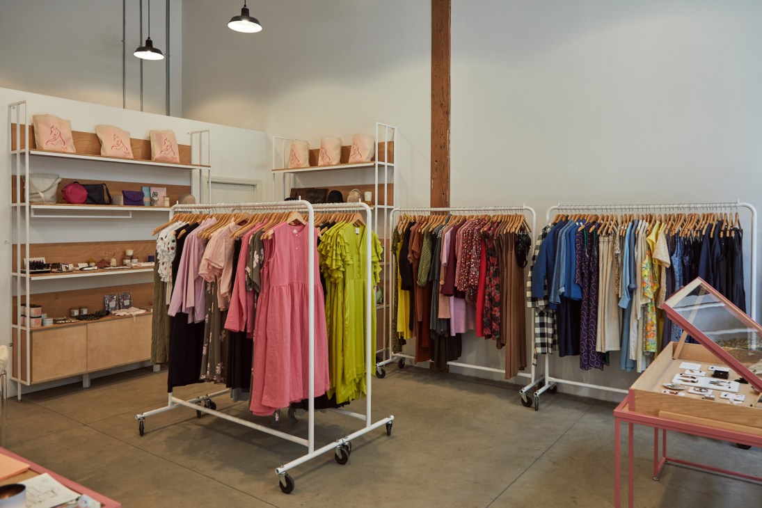 Colorful womenswear displayed on rolling racks and shelves in Myrtle boutique.