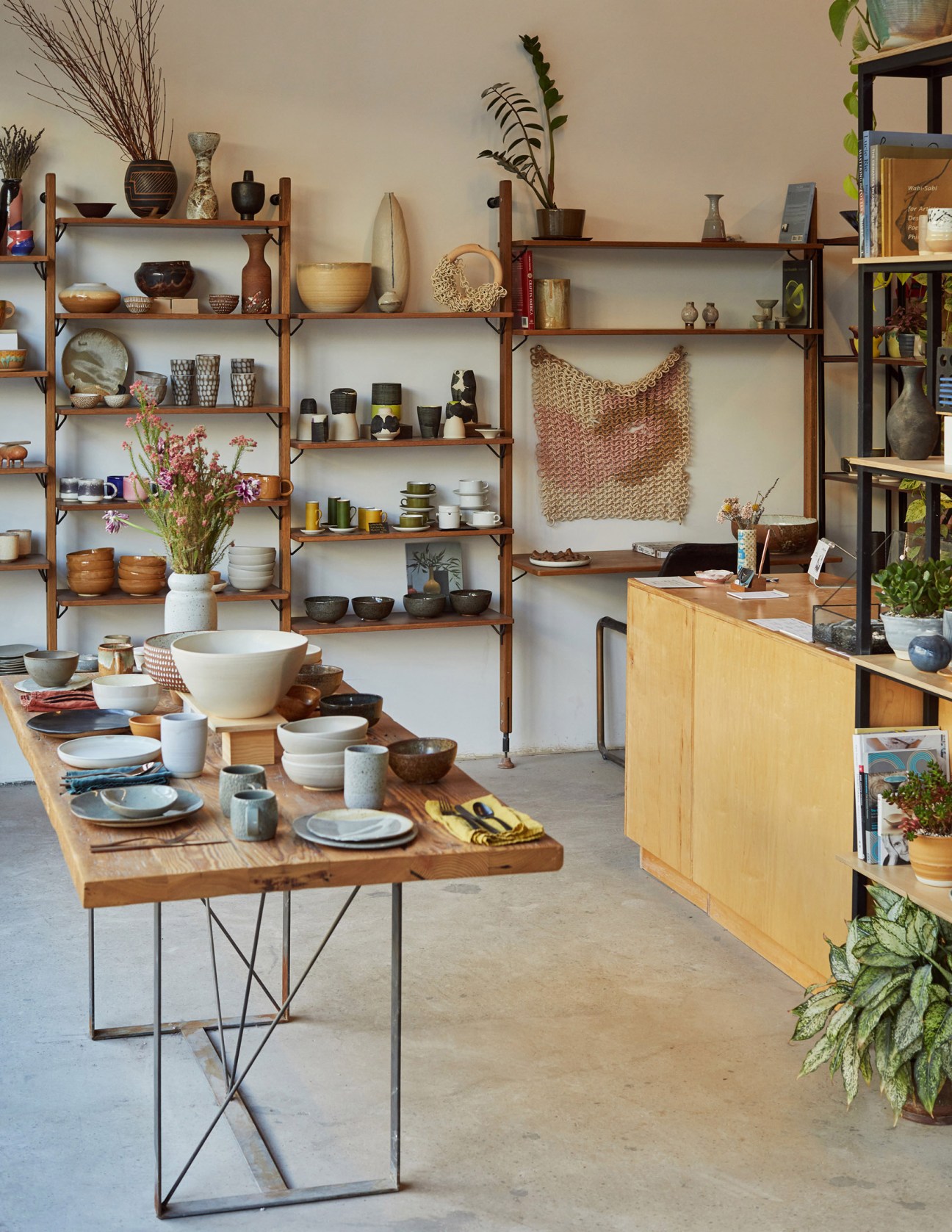 Still Life Ceramics shop interior with wooden shelving displaying ceramics, plants, and home goods.