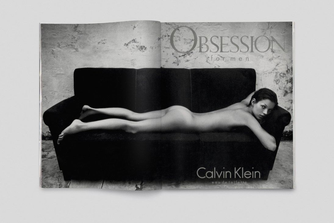 Black and white photograph of a woman reclining on a black sofa with Calvin Klein Obsession for Men branding visible in background.