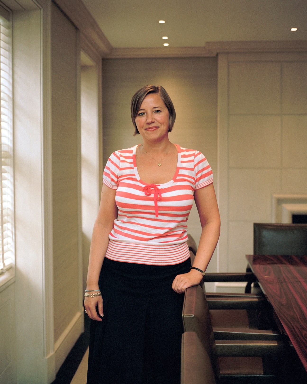Clare Harris, head of special events at Sotheby's, standing in a hallway wearing a red and white striped top.