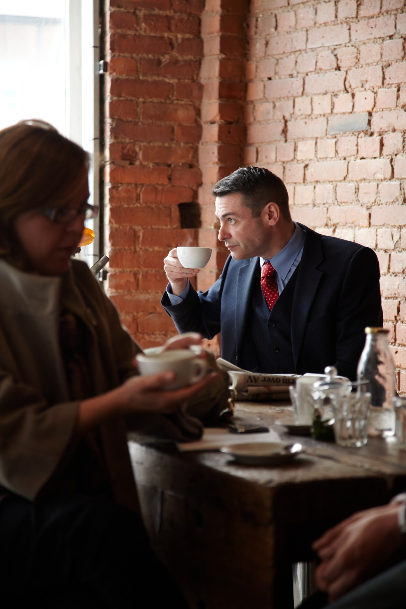 Man in business attire drinking coffee at St Ali café in London with exposed brick walls.