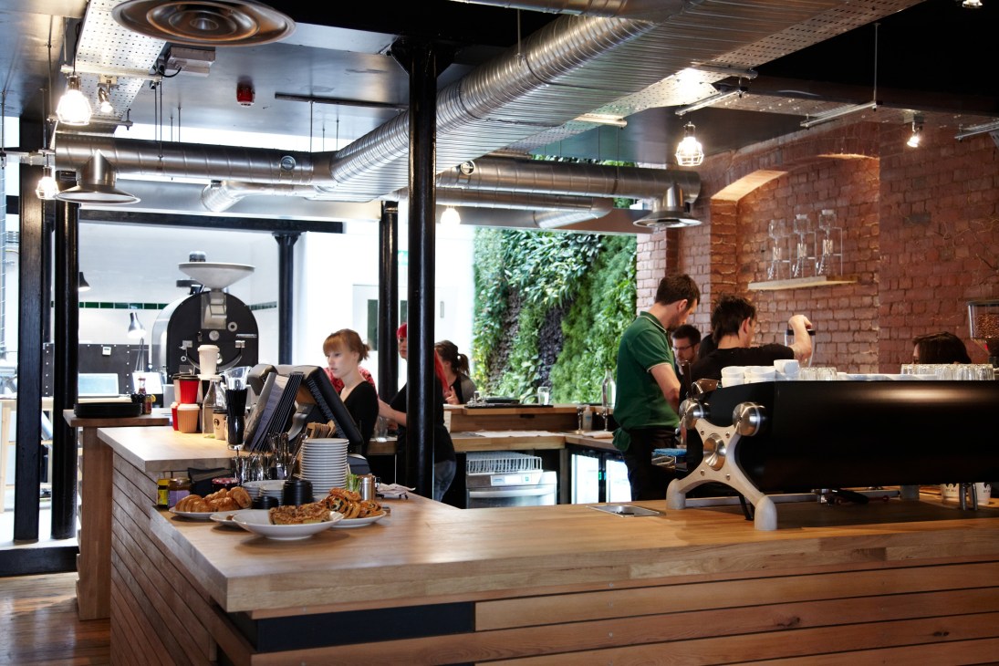 Interior of St Ali coffee roastery in London showing counter with pastries, espresso machine, and customers
