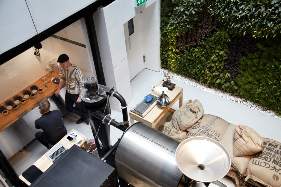 Overhead view of St Ali coffee roastery in London showing staff at counter with espresso machine and coffee equipment.