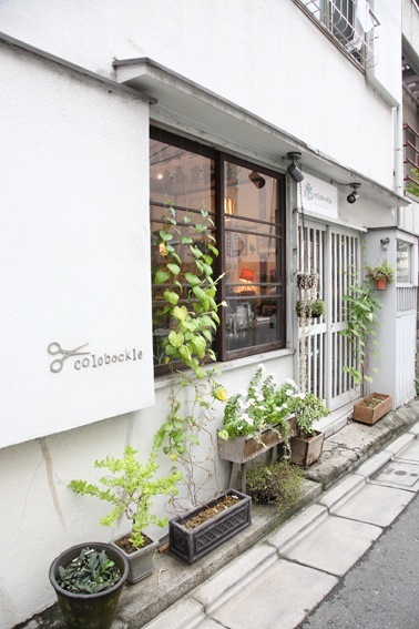 Exterior of Colobockle shop in Tokyo with white facade, large window, and potted plants at entrance.