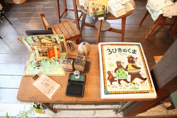Children's books and handmade crafts displayed on a wooden table in Colobockle shop.