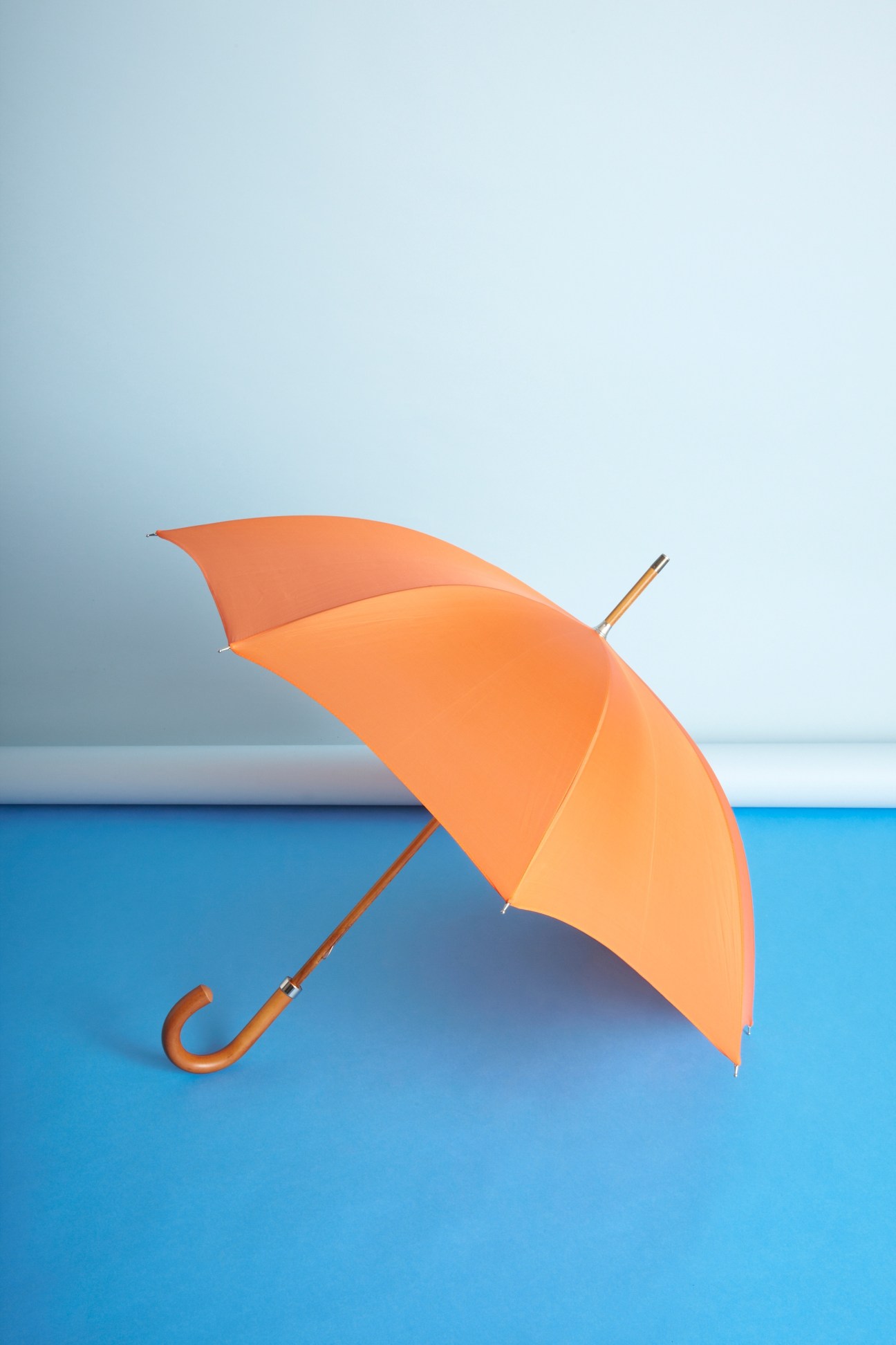 Orange umbrella by London Undercover displayed against a blue and grey background.