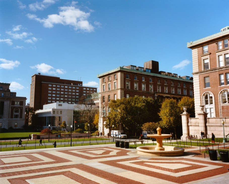 Columbia University campus courtyard with brick plaza, fountain, and historic buildings.