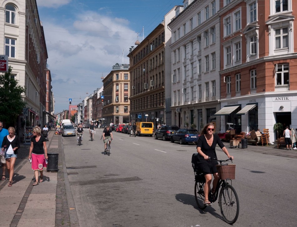 Copenhagen street scene with pedestrians, cyclists, and historic buildings lining a car-free avenue.