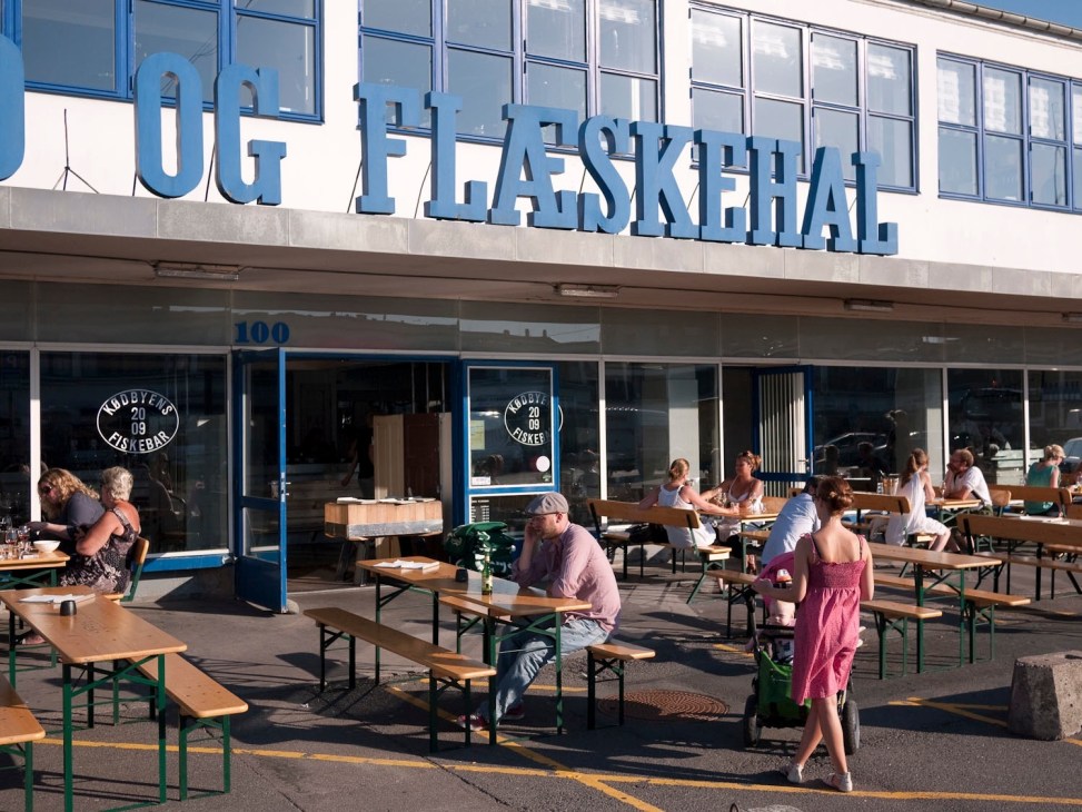 Outdoor seating area with blue signage for Og Flaskehal restaurant in Copenhagen.