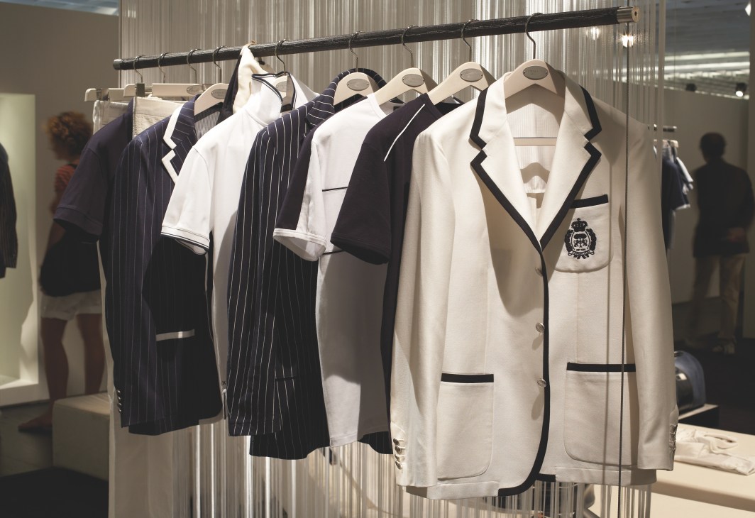 Monochrome blazers and jackets by Corneliani on wooden hangers displayed at Pitti Uomo.