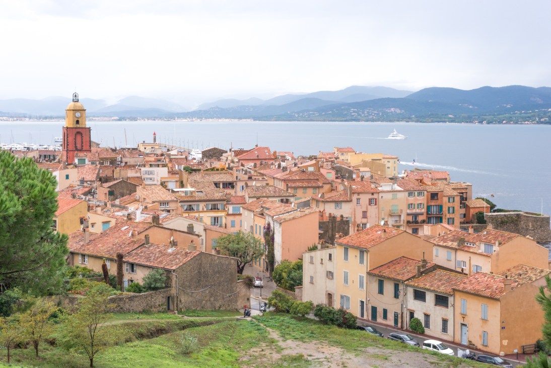 Aerial view of Saint-Tropez's colorful buildings, church tower, and Mediterranean coastline.