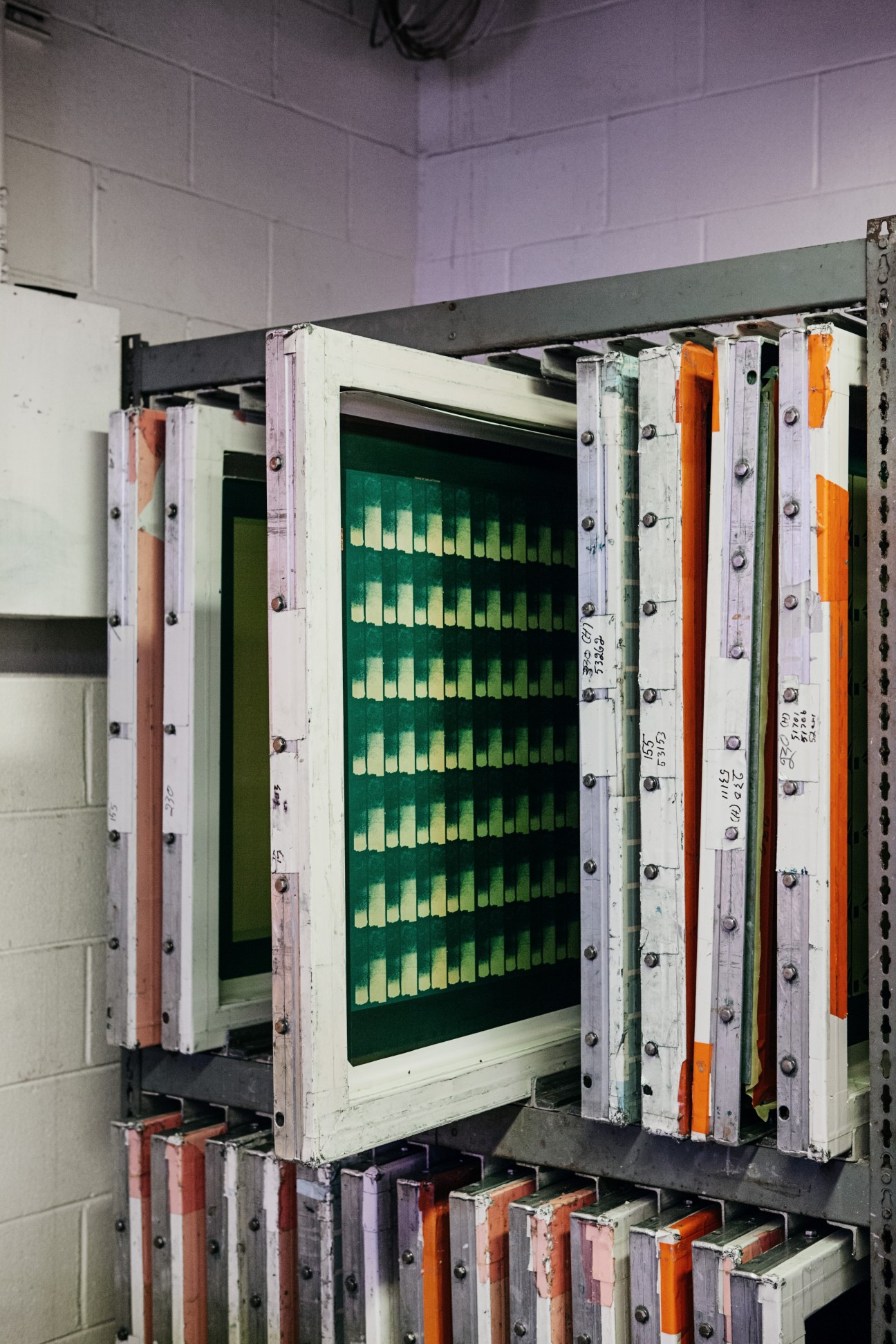 Silkscreen printing equipment with colorful ink strips and green display panel showing production data.