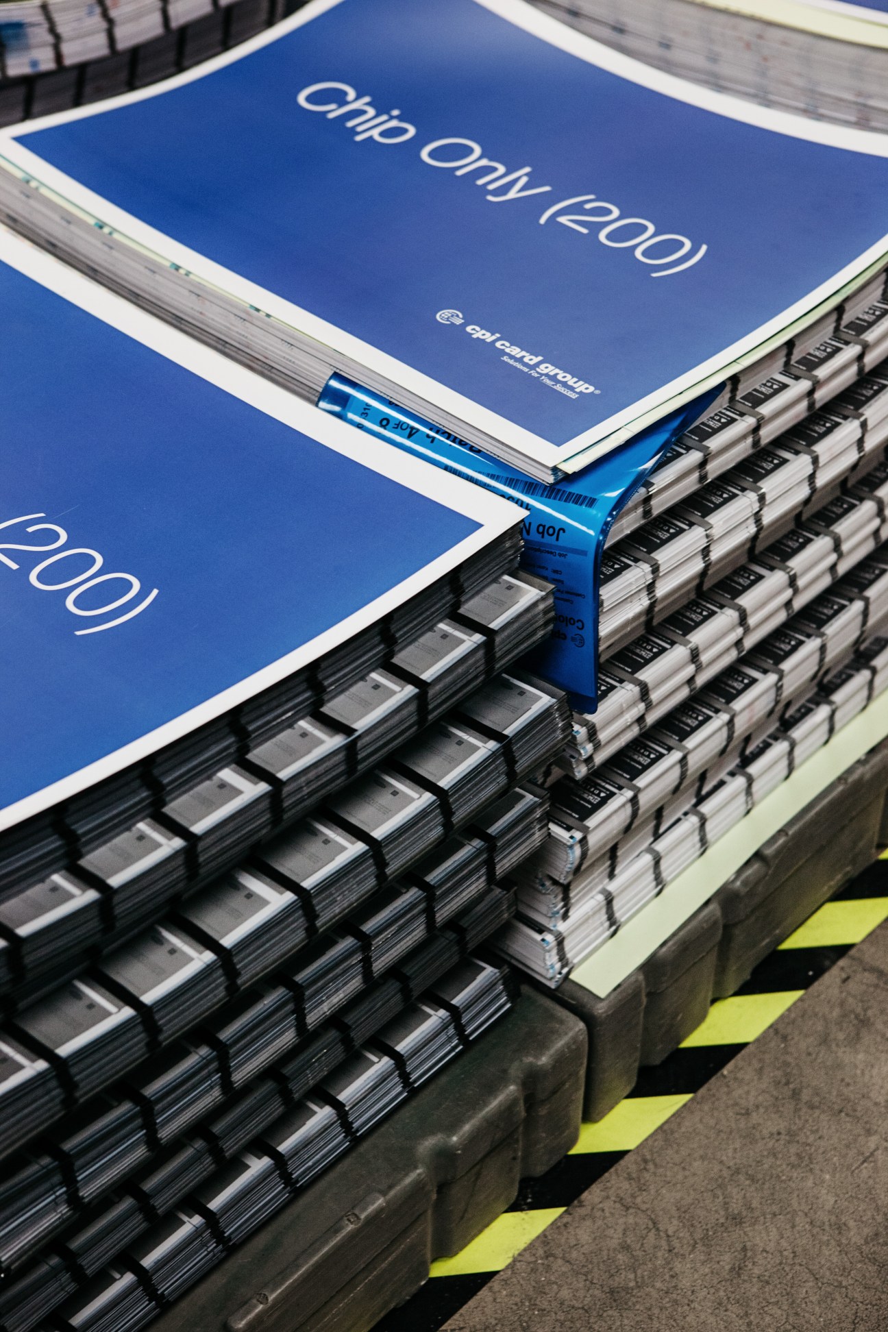 Stacks of uncut credit cards with CPI Card Group branding on blue sheets.