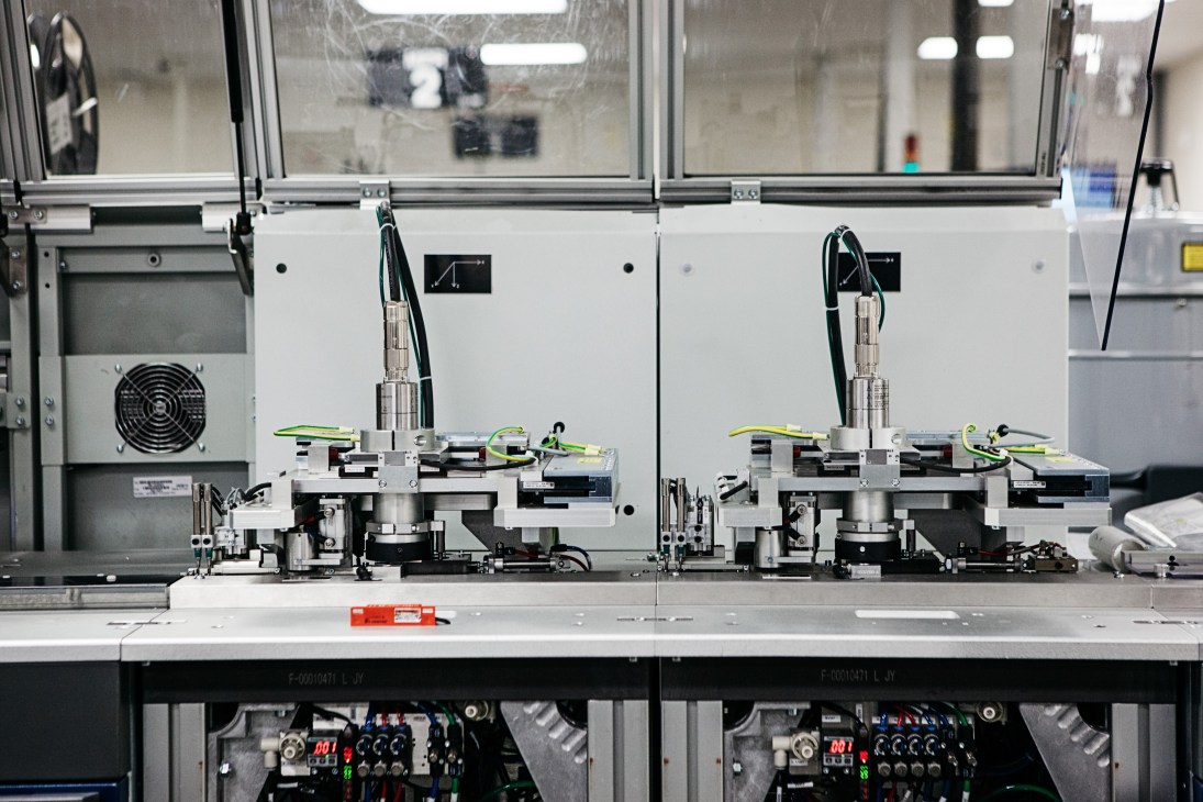 Industrial machinery with mechanical arms and control panels on a workbench for card chip installation.