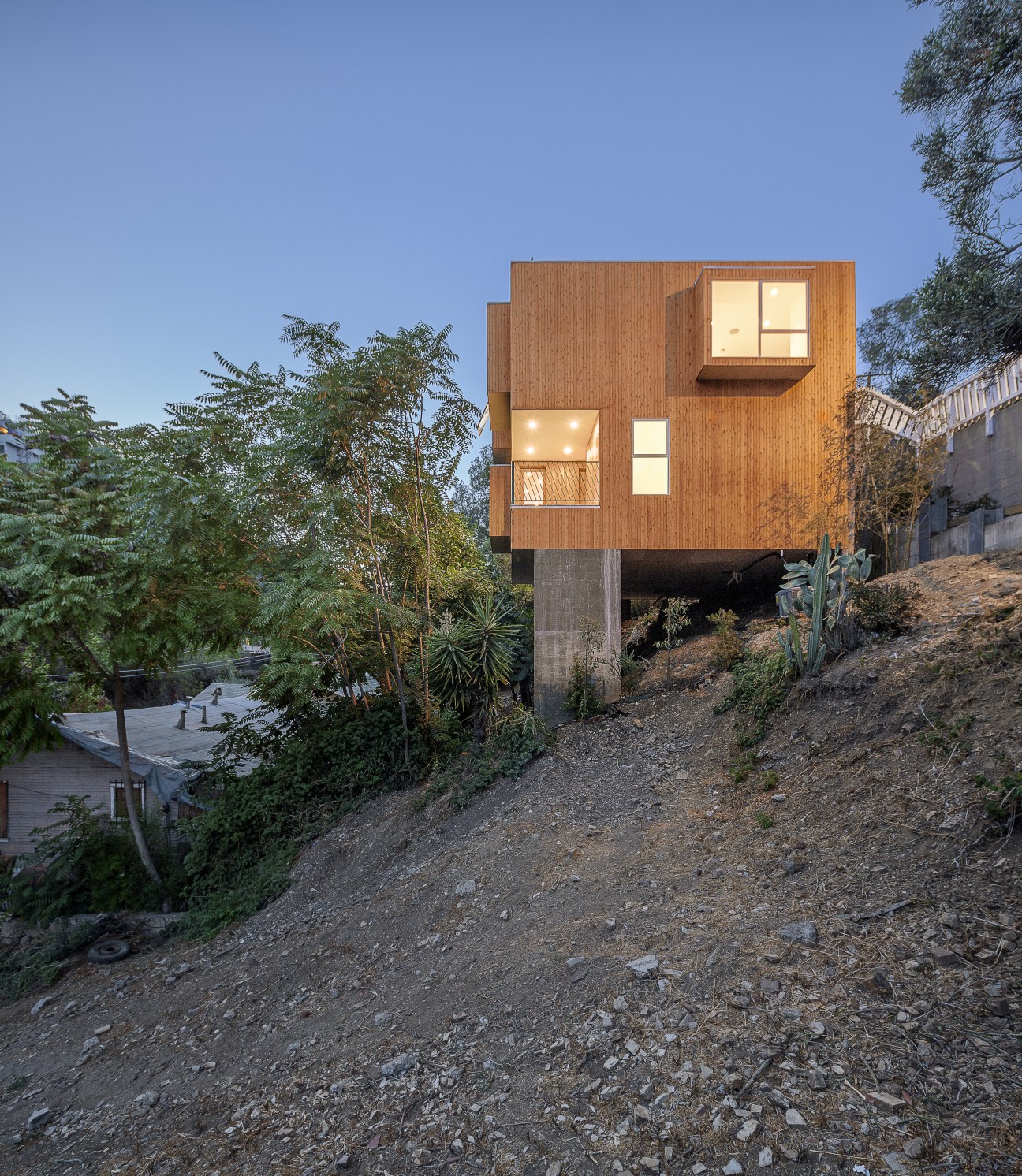 Cedar-clad compact house cantilevered on concrete piles over a sloping Mount Washington lot in Los Angeles.