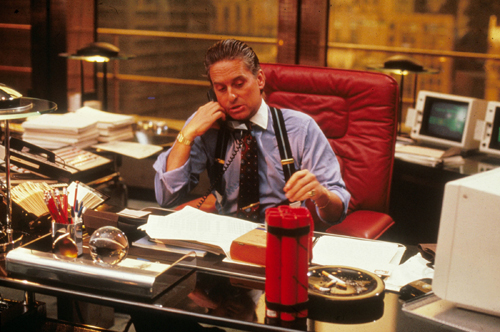 Man in pinstriped suit and tie sitting at executive desk in office from Wall Street film