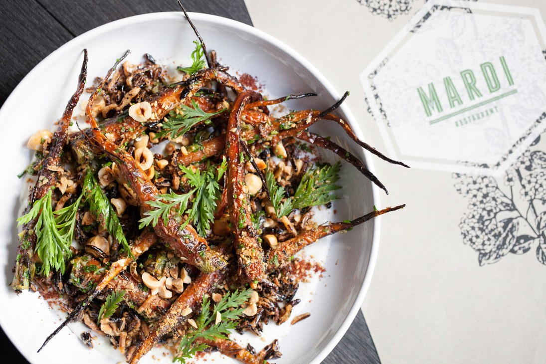 Cumin-roasted carrots with peanuts and herbs on a white plate at Mardi restaurant.