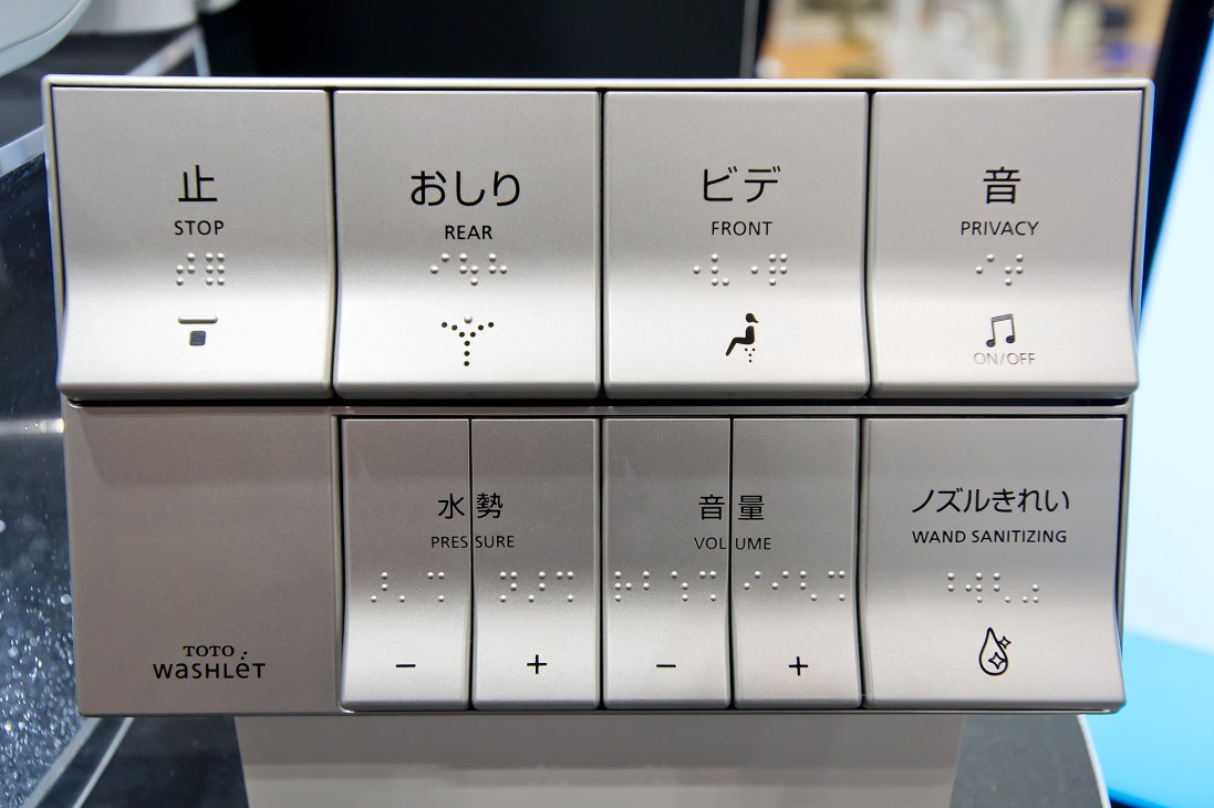 Toto Washlet control panel with Japanese and English labels for stop, rear, front, privacy, pressure, volume, and wand sanitizing functions.