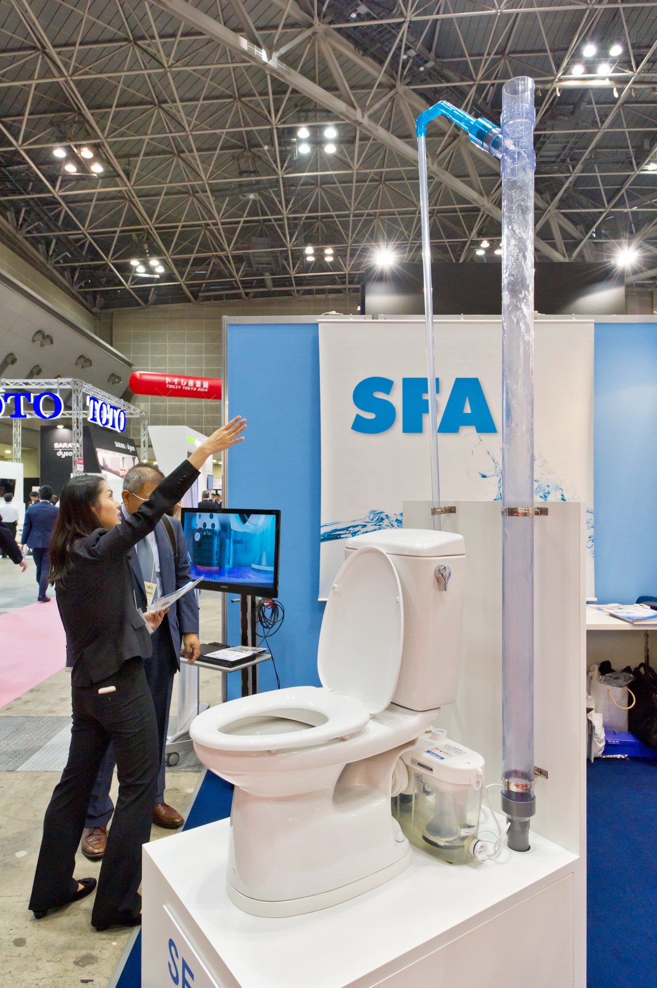 Woman demonstrates France's SFA toilet system at Toilet Tokyo convention booth.