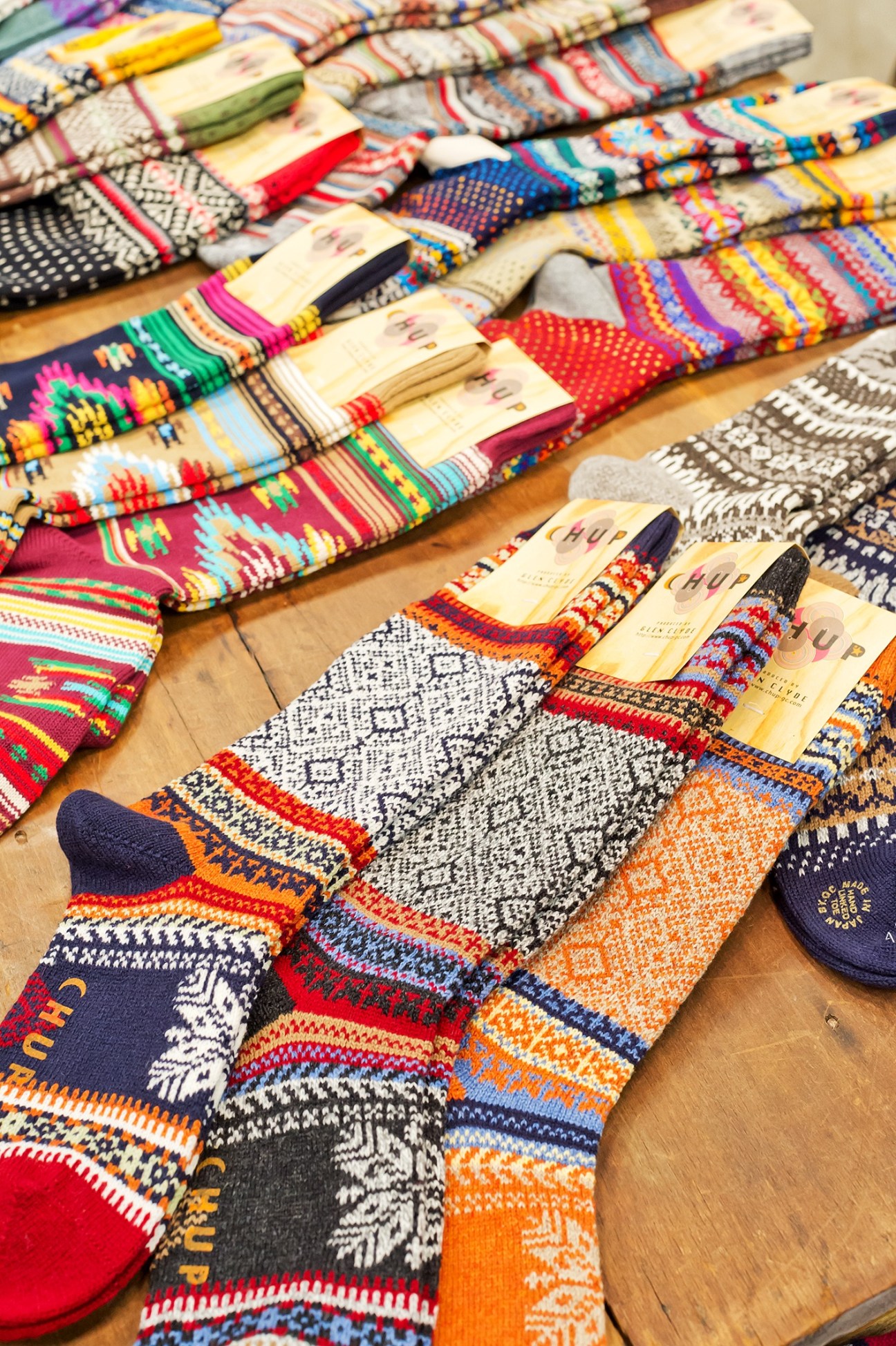 Colorful patterned Chup socks with branded labels arranged on a wooden surface.