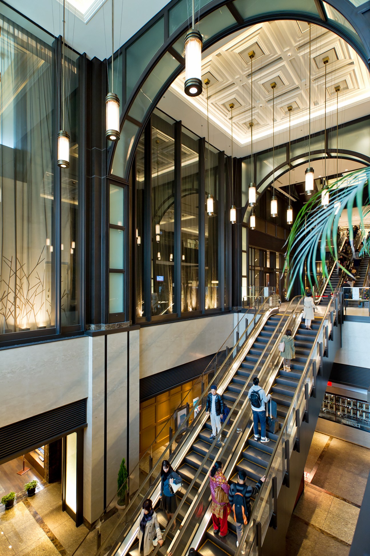 Interior atrium of Shin Marunouchi Building with escalators, black metal framing, and pendant lighting.