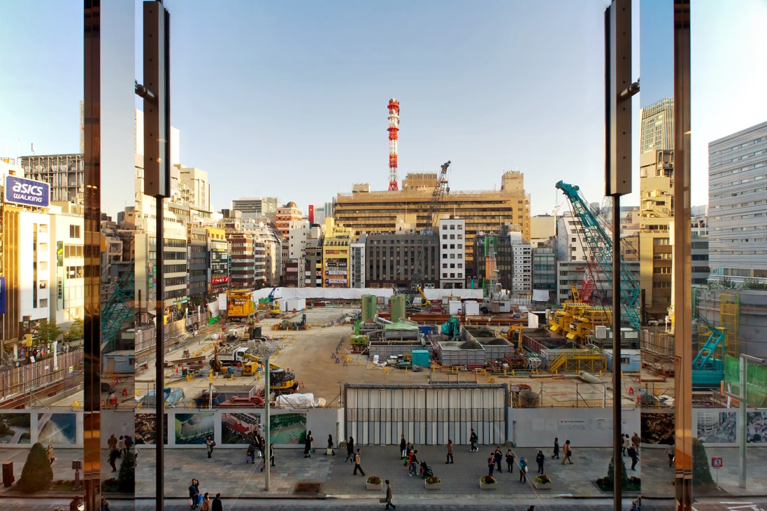 Tokyo construction site viewed through building windows showing urban redevelopment in Marunouchi district.
