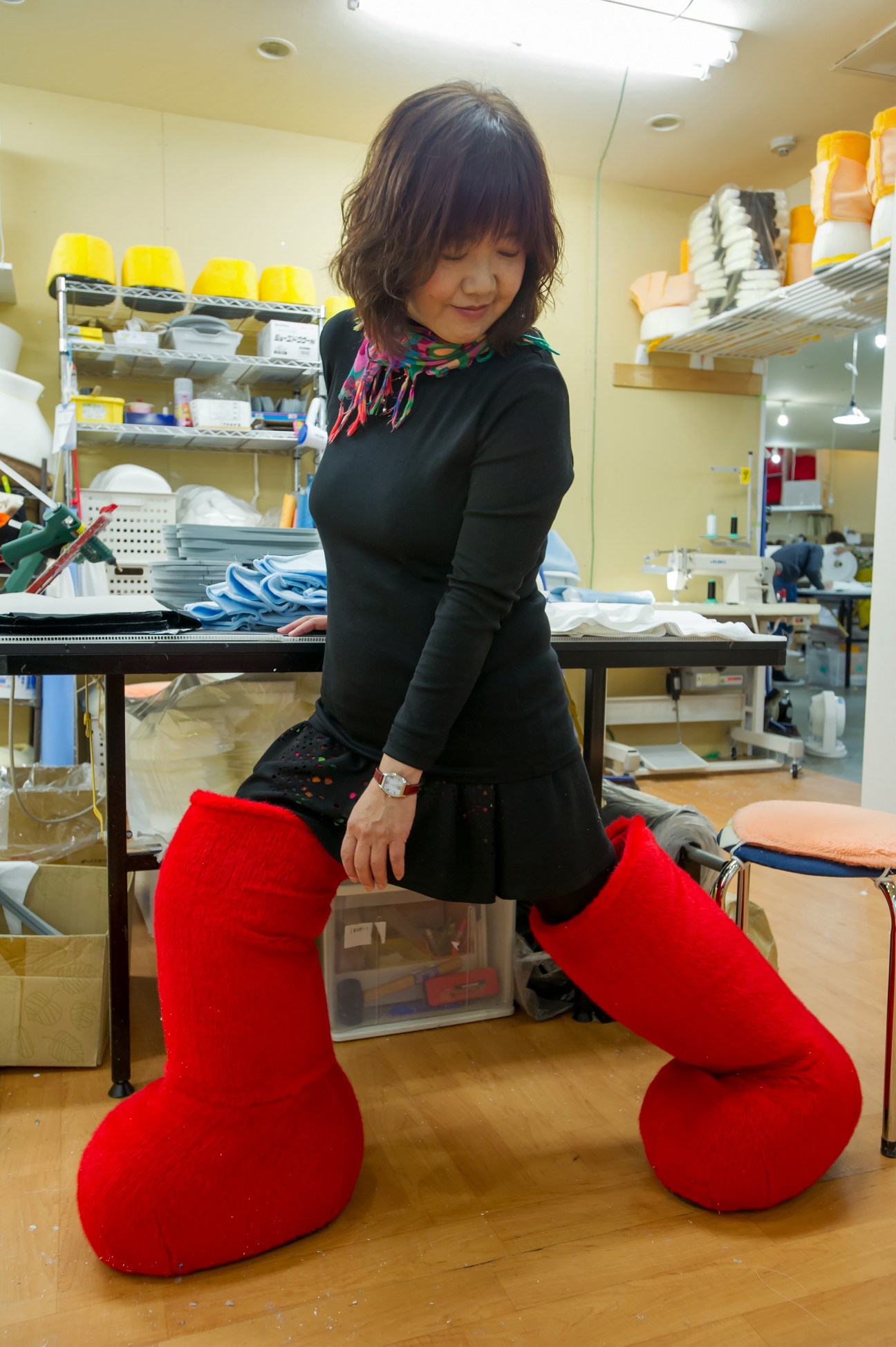 Hiromi Kano wearing red furry Biz Bear legs in her mascot factory workshop.