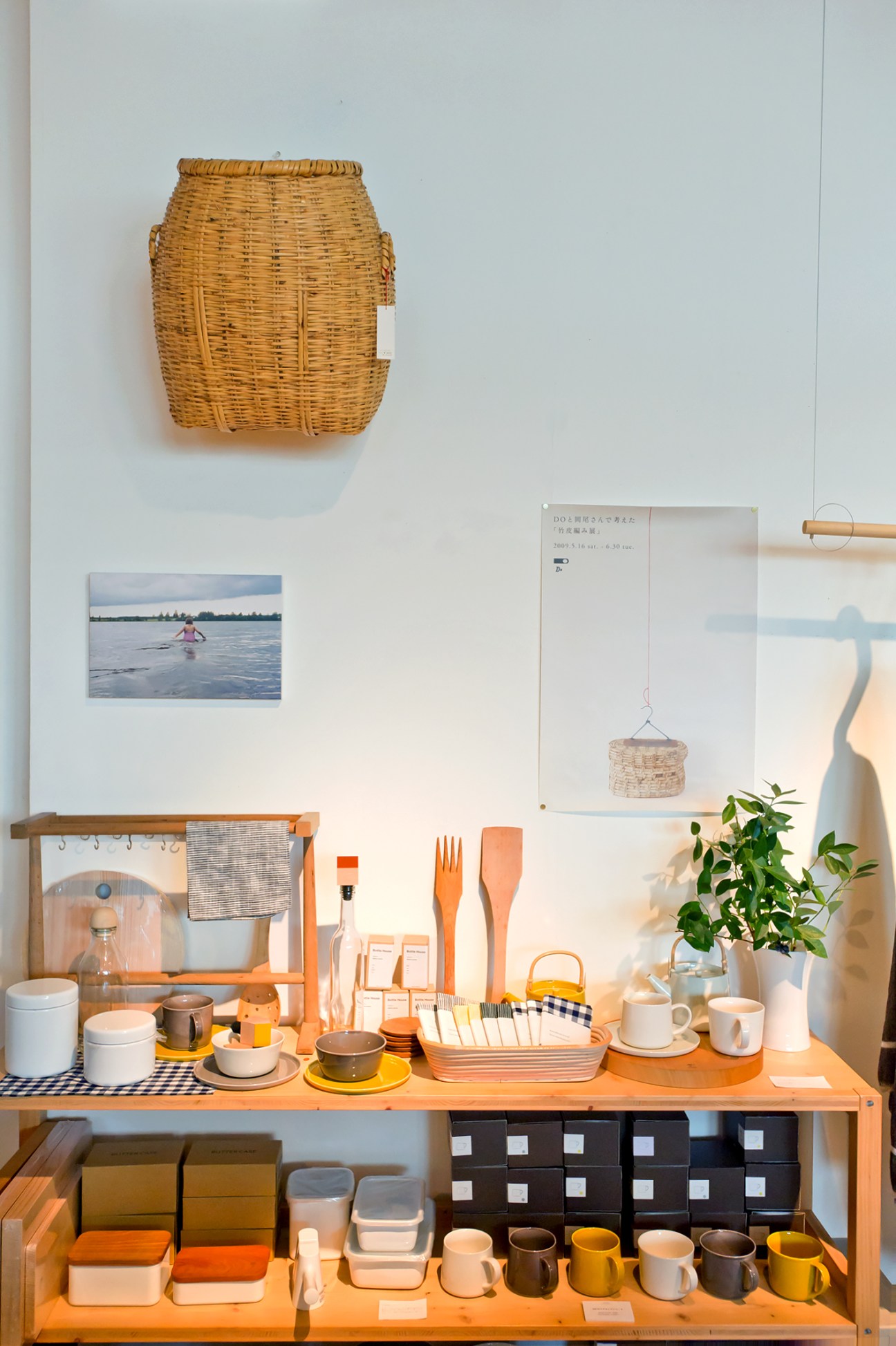 Display of Japanese homeware at Claska Shop featuring white ceramics, orange kitchen utensils, and woven baskets.