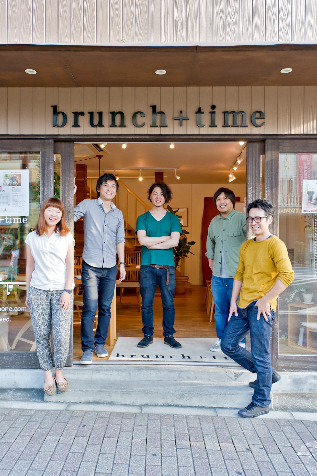 Five smiling staff members standing in the doorway of Brunch + Time furniture shop on Meguro Dori.