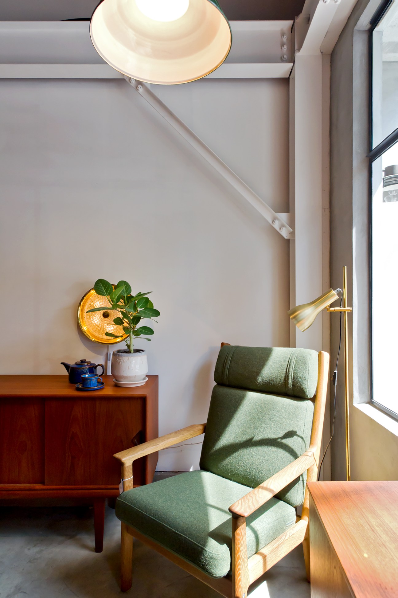 Hans J Wegner lounge chair with green upholstery and wooden arms in a minimalist interior space.