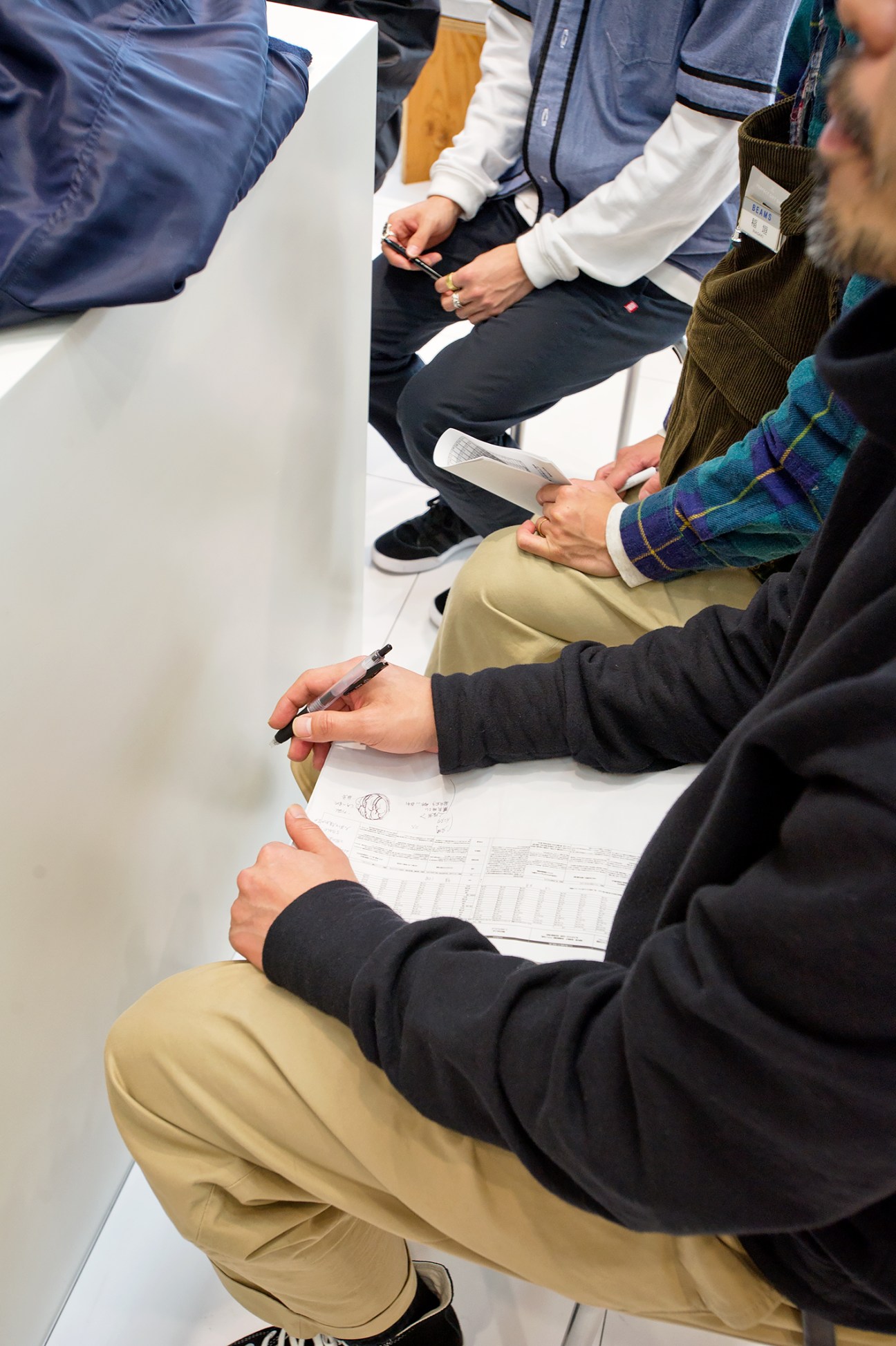 Beams shop staff sitting in a circle taking notes during a styling training session.