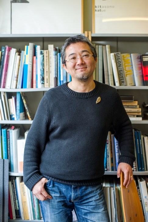 Seiichi Kozu, founder of Studio Koz and Real Kanazawa Estate, standing in front of bookshelves in his office.