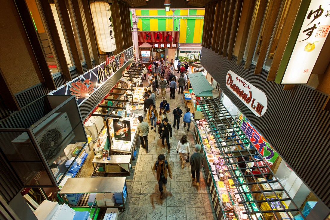 Overhead view of Omi-cho market with rows of vendor stalls and shoppers walking through the covered market hall.