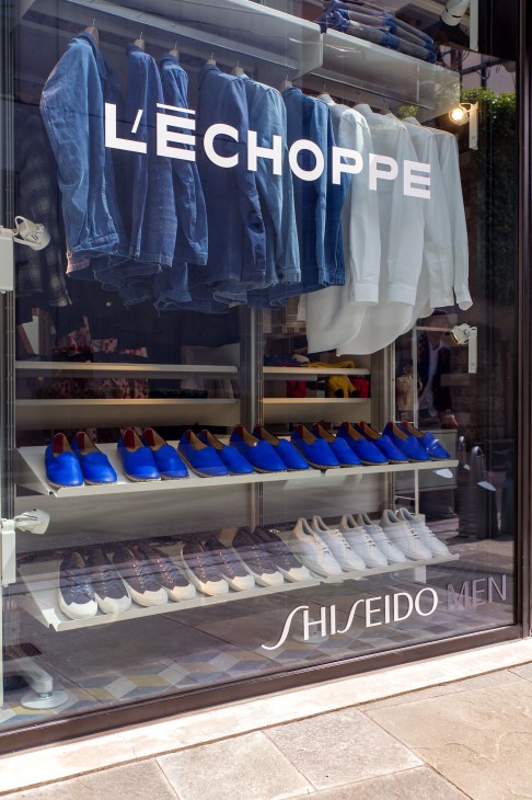 L'échoppe Tokyo storefront window displaying denim shirts and blue shoes with Shiseido Men branding.