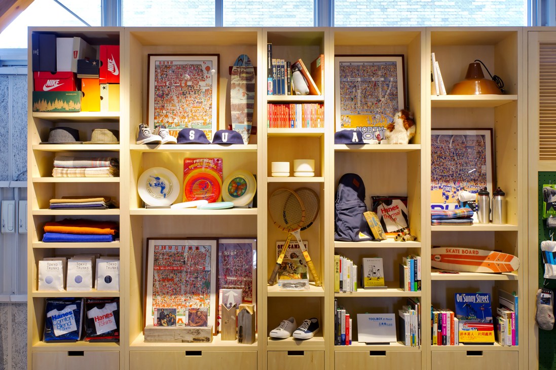 Wooden shelving units displaying menswear, books, home goods, sports equipment and decorative items in La Kagu Tokyo shop.