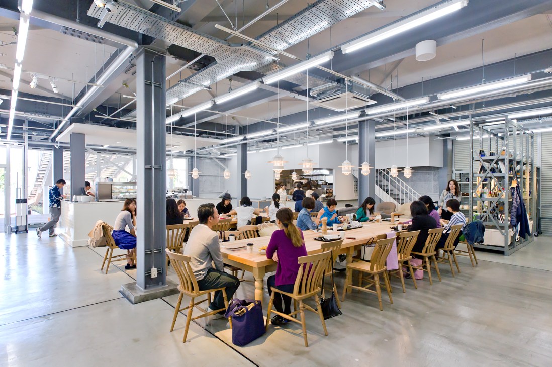 La Kagu café interior with customers seated at long wooden tables under pendant lights in a warehouse space.