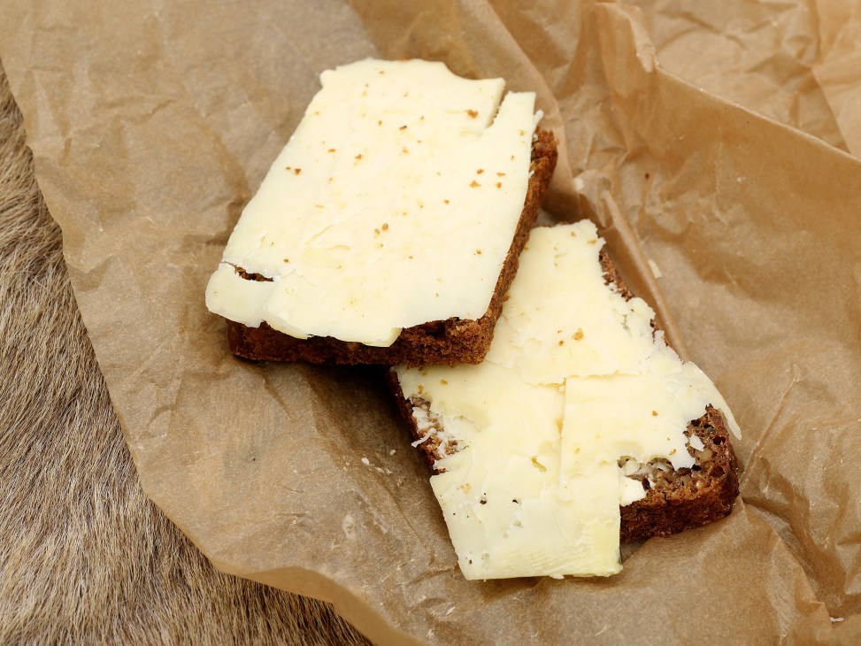 Slices of rye bread topped with mature cheddar cheese on parchment paper.