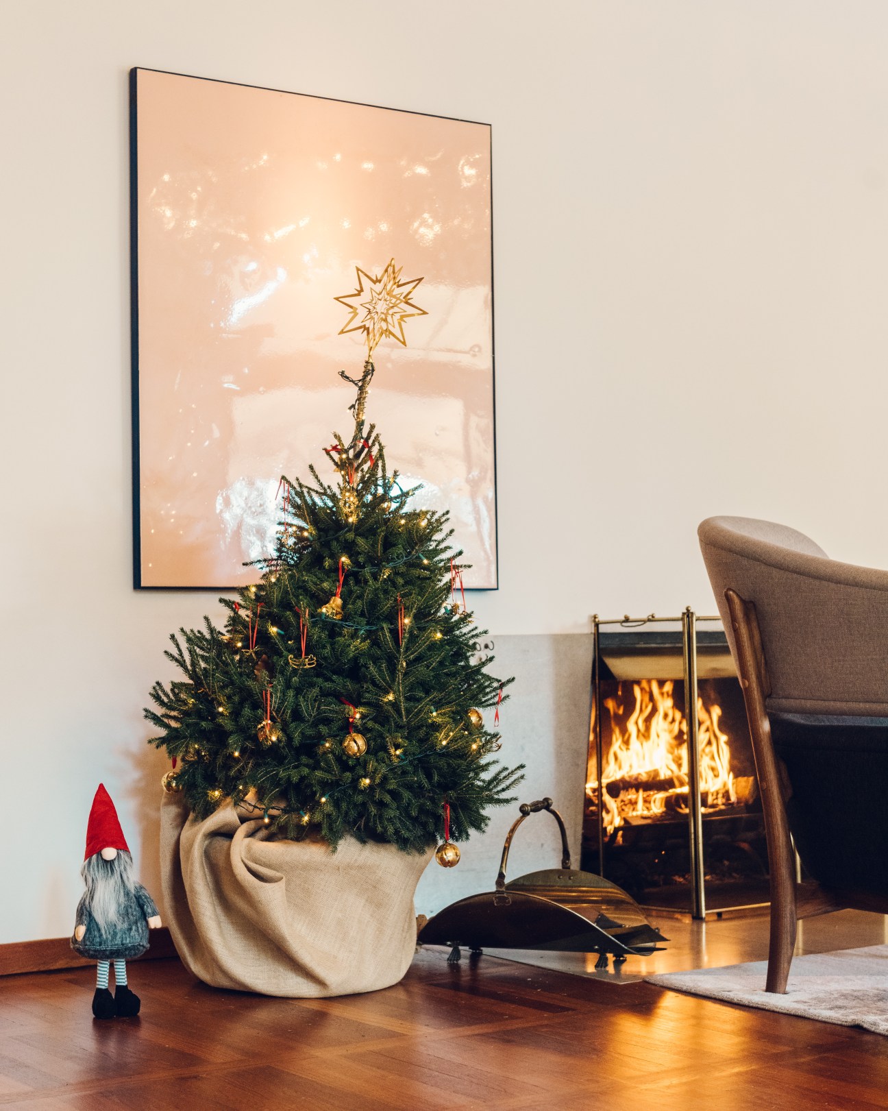 Decorated Christmas tree with gold star topper and ornaments next to a red nisse gnome figurine, Danish embassy.