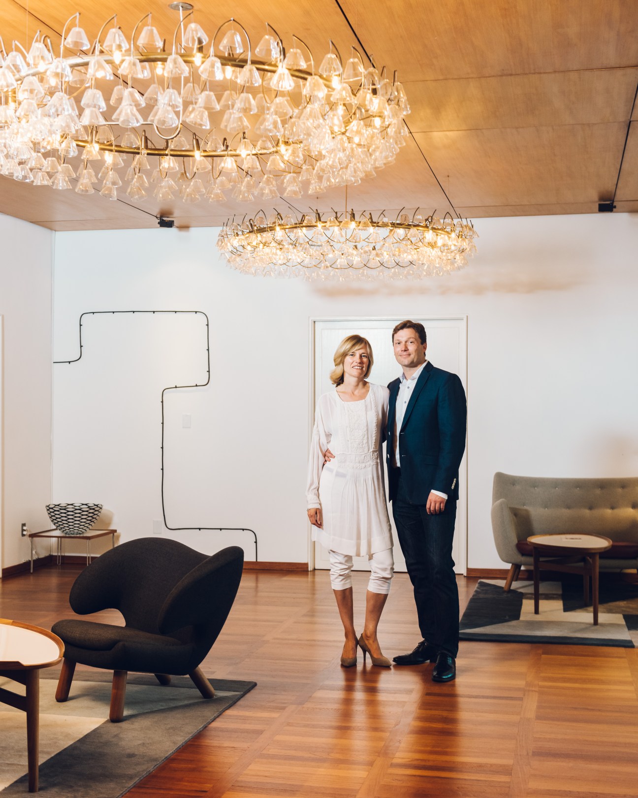 Danish ambassador Lars Gert Lose and his wife Ulla Rønberg stand in an elegant modern interior with crystal chandeliers.